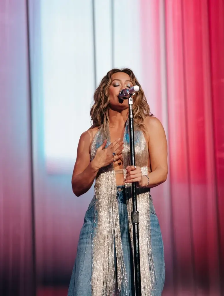 Hilary Duff in a blue feathered top and jeans on stage