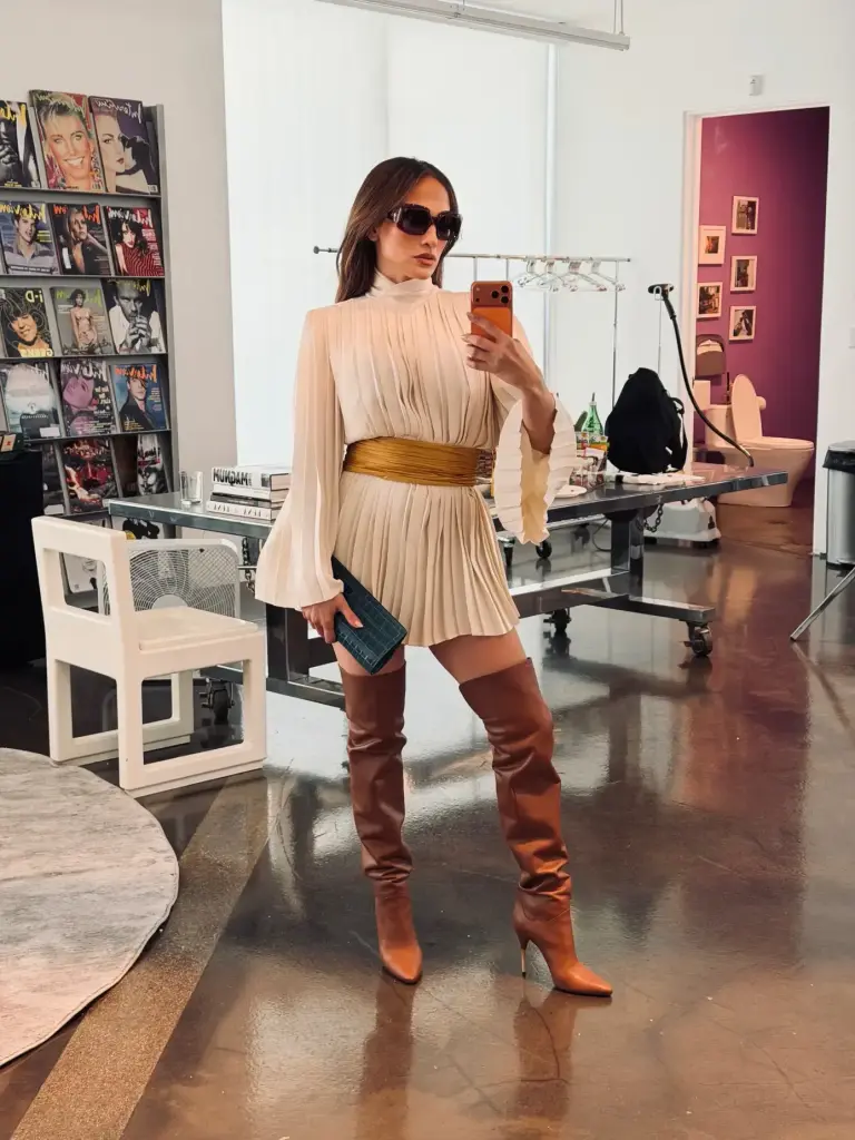 Jennifer Lopez poses with the collectible album amid red walls, glowing lanterns, a disco ball and vintage televisions.