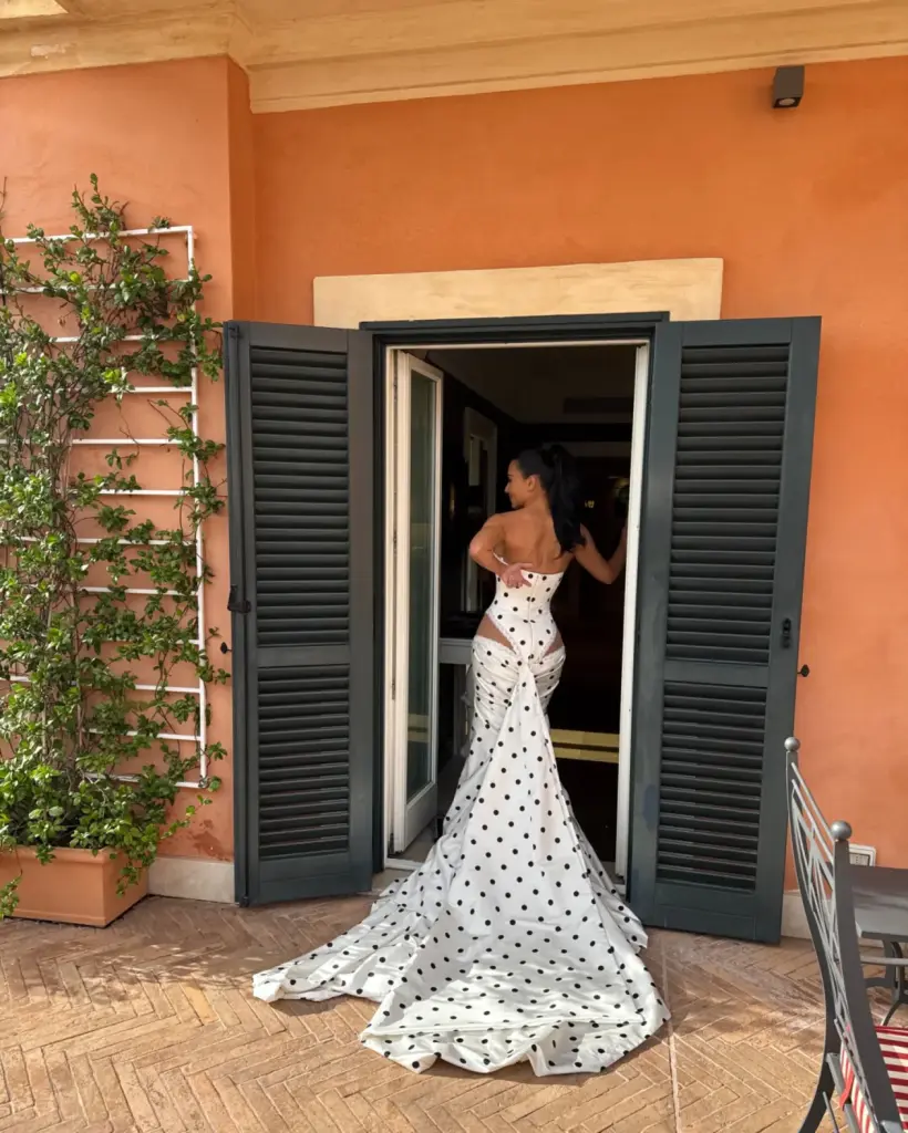 Kim Kardashian in a draped polka-dot gown with a long train, joined by two Dalmatians