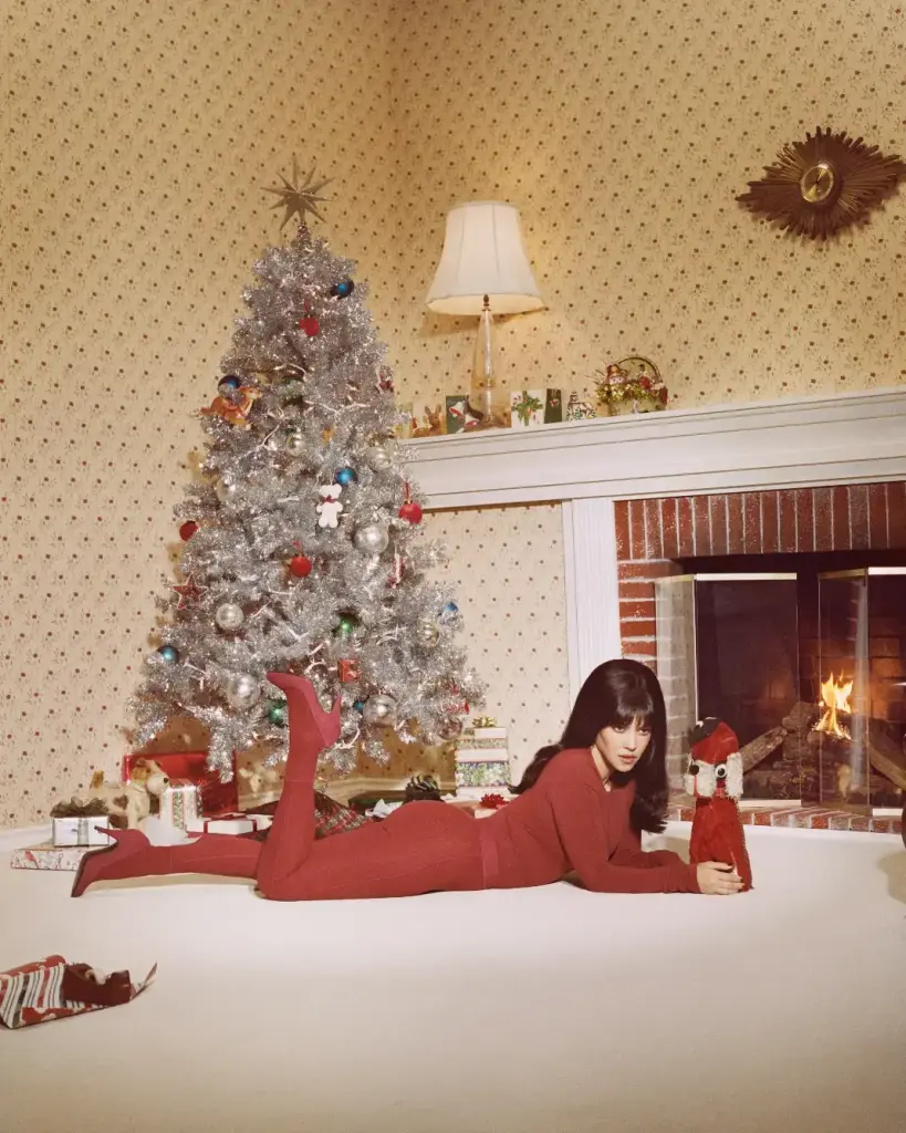 Kardashian-Jenner sisters in a Christmas setting with tinsel trees, presents and a fireplace