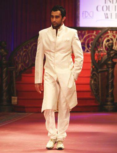 A man wearing a fitted achkan with a high Nehru collar and full-length front button closure