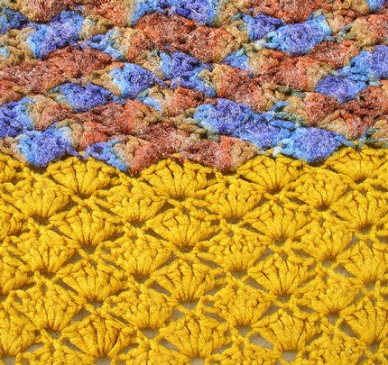 A hand-crocheted afghan blanket worked in bright yarns with repeating geometric motifs