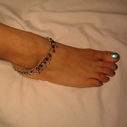 A fine chain anklet worn around a bare ankle, sitting just above the ankle bone